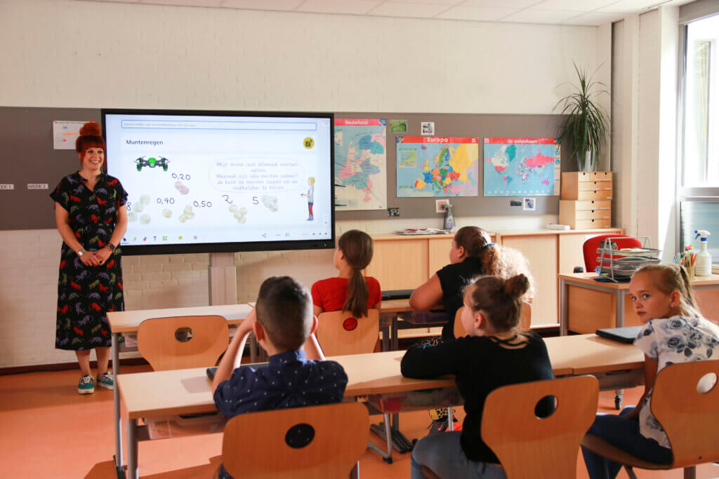 a classroom with student sat at their desk looking at their interactive whiteboard